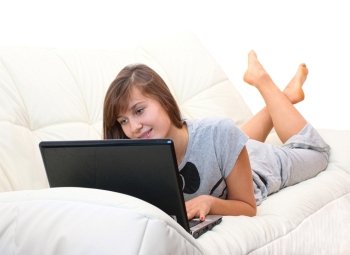 teenager girl lying on the sofa with a laptop and smiling isolated