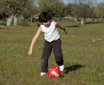 Small child playing soccer in the field