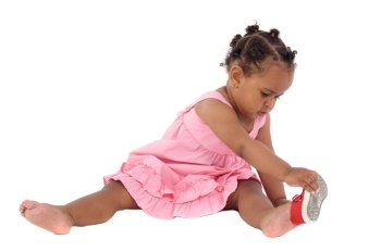 Beautiful african baby girl putting on an slipper on a white background