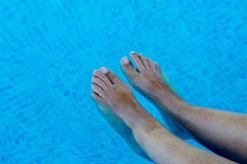 a photo of feet refreshing in swimming pool in summer