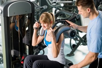 Fitness center young woman exercise with personal trainer on gym machine