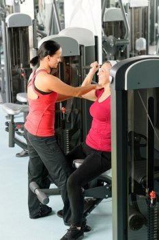 Happy senior woman at gym workout with personal trainer assistance