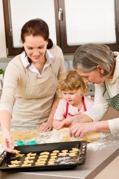 Happy little girl rolling out dough with mum and grandmother
