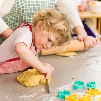 Little girl cutting out dough for cookies cute blond child