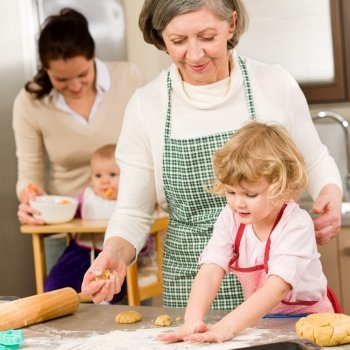 Grandmother with little girl prepare dough for baking in kitchen