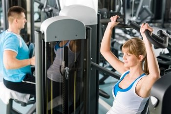 Active man and woman at fitness center exercise on machine