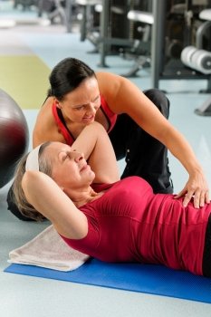 Fitness center senior woman exercise with personal trainer on mat