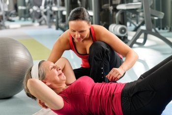 Fitness center senior woman exercise with personal trainer on mat