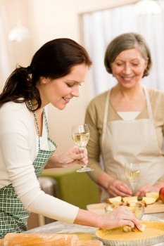 Two happy women enjoy baking apple pie drink white wine