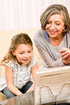 Grandmother teach young girl learn music notes play flute smiling