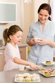 Little girl pointing cupcake to her mother happy at home