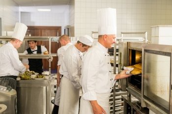 Group of cooks in professional kitchen prepare meals restaurant service