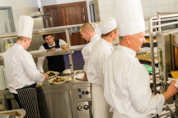Group of cooks in professional kitchen prepare meals restaurant service