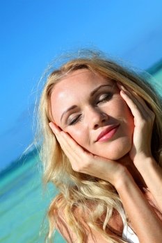 Blond woman at the beach with hands on chin