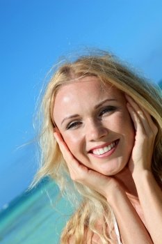 Blond woman at the beach with hands on chin