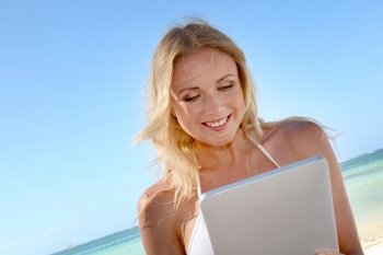 Blond woman using electronic tablet at the beach