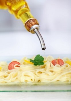 Closeup on on olive oil being poured on pasta dish