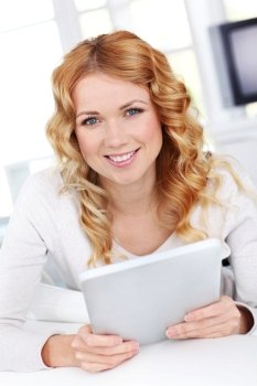 Blond woman relaxing in sofa using electronic tablet