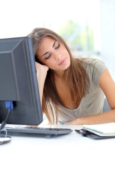 Exhausted young woman sitting in front of computer