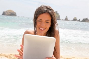 Beautiful woman in bikini using tablet on the beach
