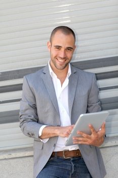 Man leaning on wall with electronic tablet