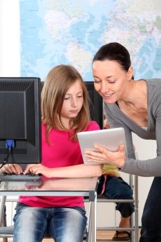 Teacher showing electronic tablet to school girl