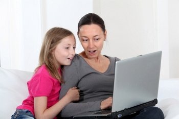 Mother and daughter using laptop computer at home
