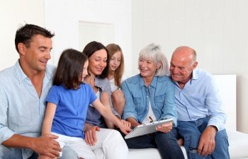 3-generation family sitting in couch with electronic tablet