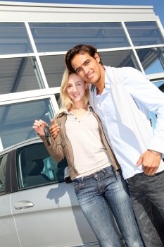 Couple holding car key in automobile dealership