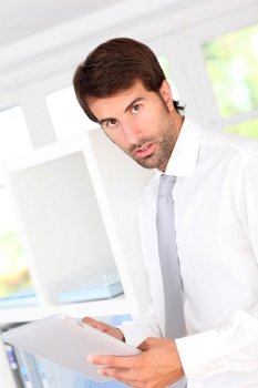 Portrait of businessman in office using electronic tablet
