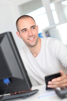 Smiling office worker sitting in front of desktop computer