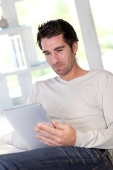 Man relaxing at home with electronic tablet