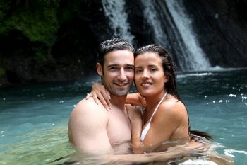 Happy couple bathing near waterfall in island
