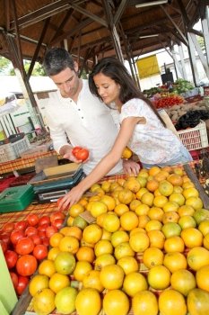 Cheerful couple choosing fruits in outdoor market