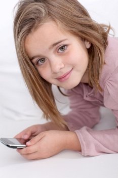 Portrait of little girl writing short message on mobile phone