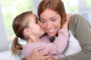 Portrait of little girl kissing her mom