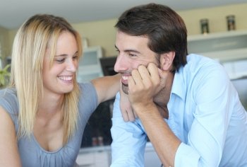 Happy young couple standing in home kitchen