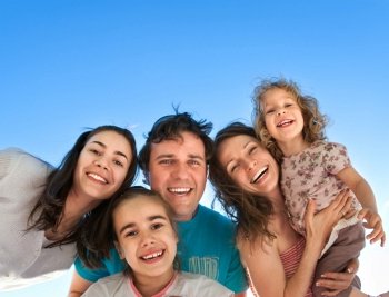 Group of happy smiling friends: man, women and kids having fun outdoors against blue sky background. Summer vacations concept