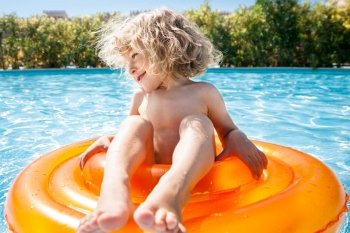 Happy child playing in blue water of swimming pool on a tropical resort at the sea. Summer vacations concept