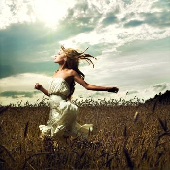 Portrait of romantic woman running across field