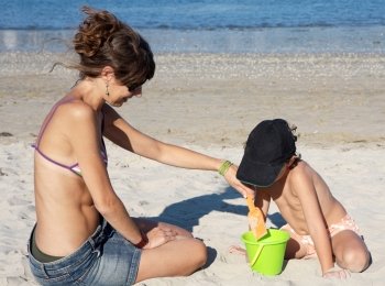 Child and woman playing on the beach