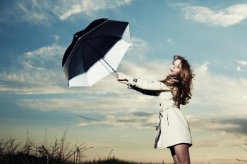 Fashion portrait of elegant woman in a raincoat on the nature. Woman with an umbrella