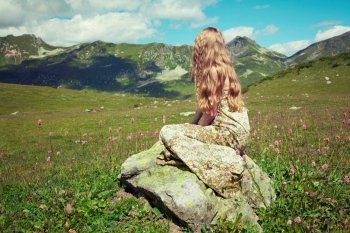 Beautiful young woman in mountains on a meadow