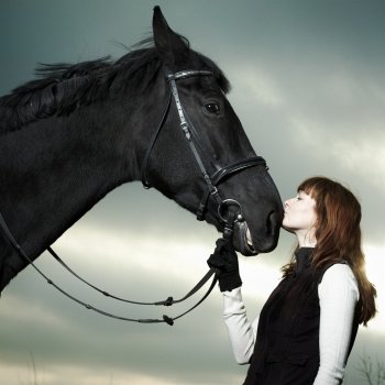 Beautiful young woman with a black horse