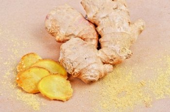 Fresh, dried and powdered ginger at brown background