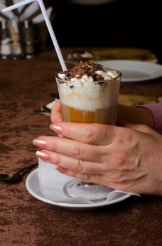 Closeup of female hands holding cup of latte