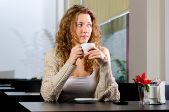 young woman is sitting at cafe and looking sideways