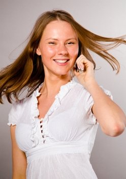 beautiful young caucasian woman on gray background is talking phone