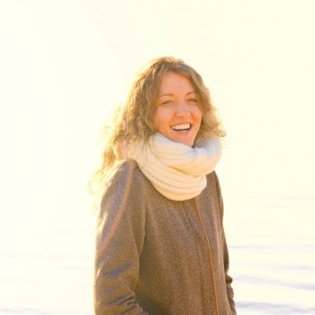 smiling woman at sea coast in winter, yellow toned