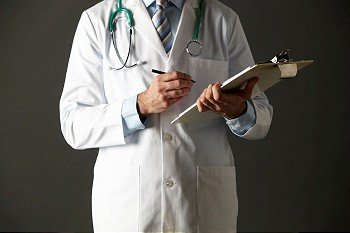 horizontal,indoors,studio shot,black background,doctor,consultant,stethoscope,clipboard,holding,pen,writing,health service,hospital,practice,medical,healthcare,white coat,shirt,tie,mid section,front view,shadow,people,one person,male,man,caucasian,adult,30s,thirties,cropped,american,usa
